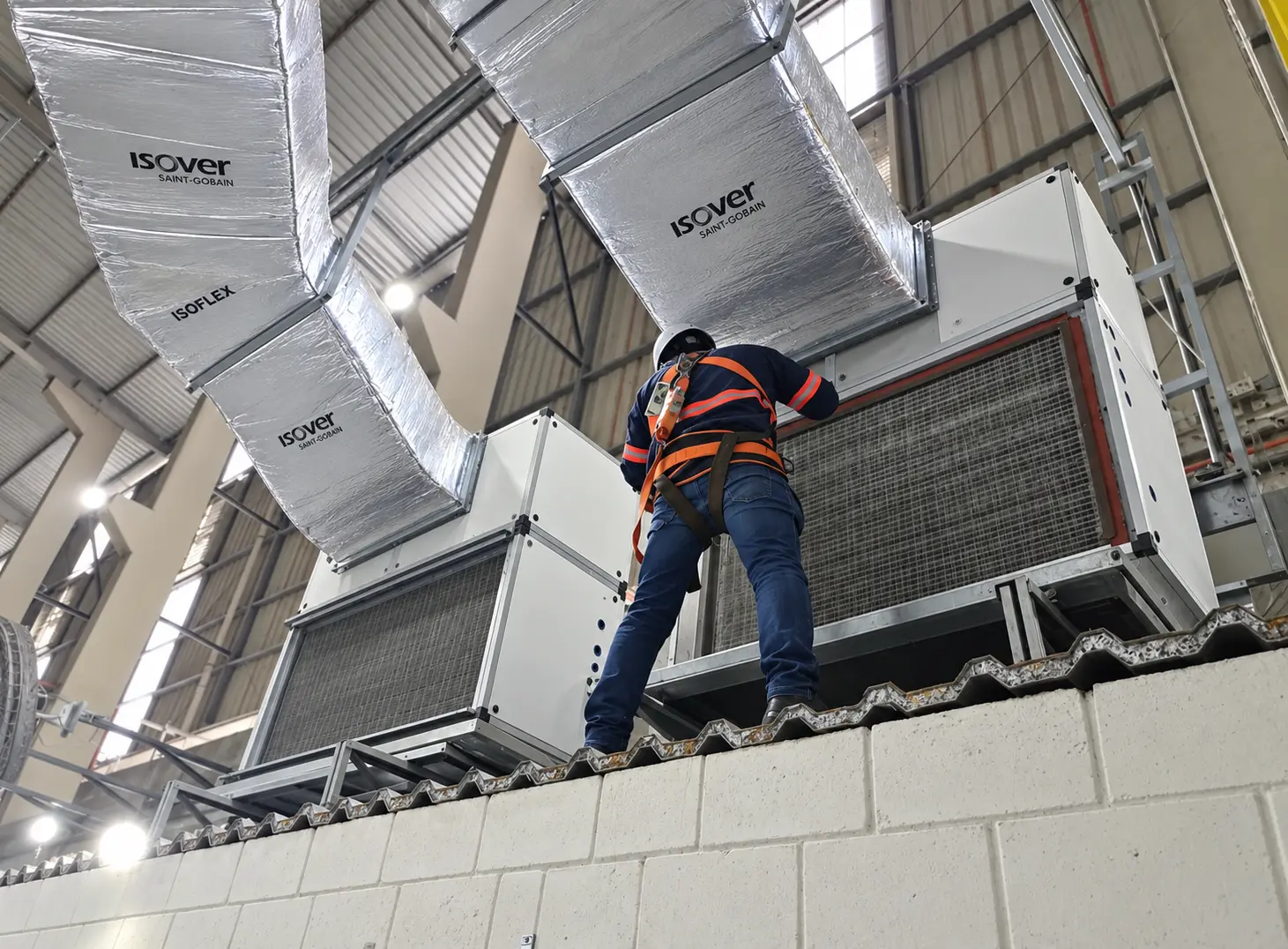 Técnico com equipamento de segurança executando serviço em sistema HVAC industrial