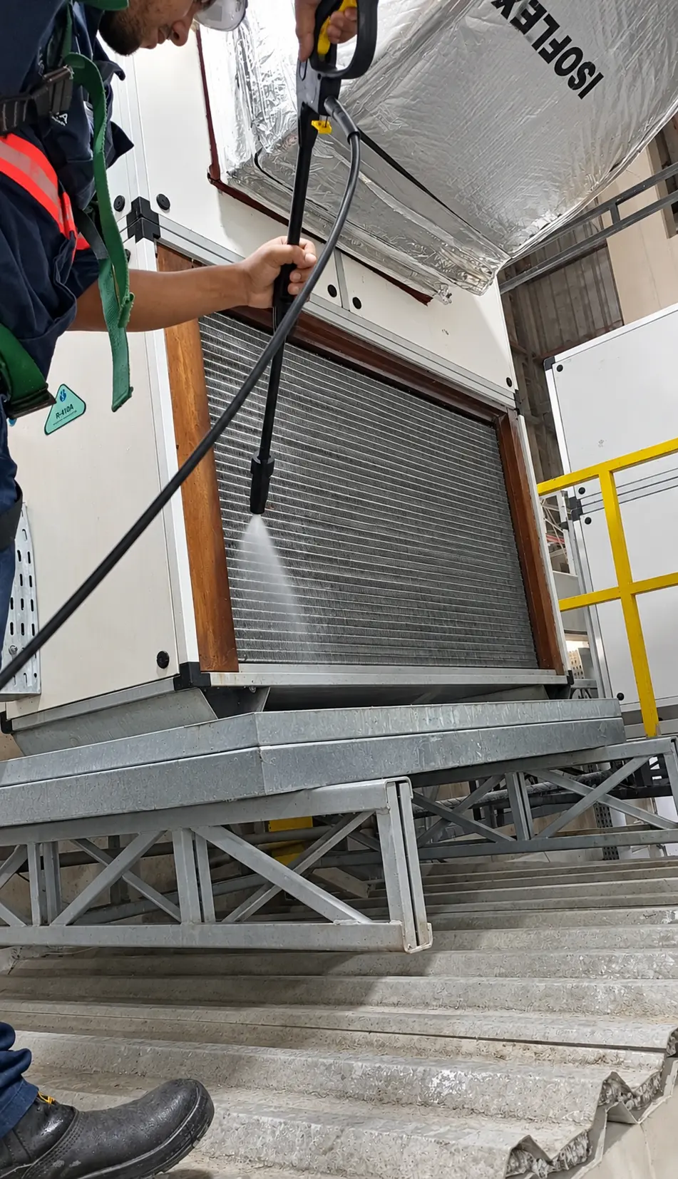Técnico higienizando serpentina de equipamento de climatização com lavadora de pressão